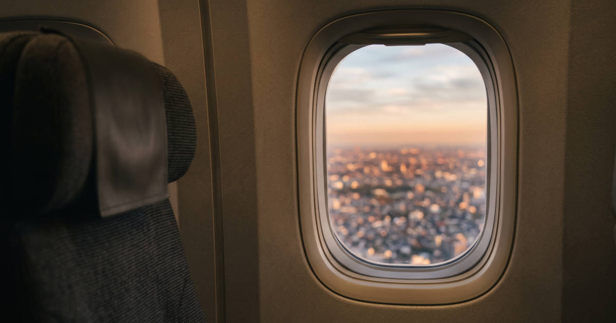 Vista da janela de um avião, com uma cidade ao anoitecer lá embaixo